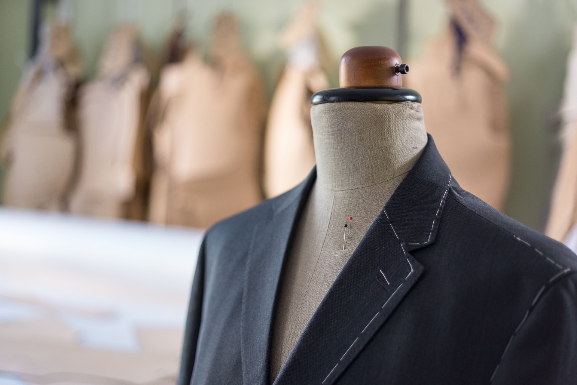 Tailored suit jacket with alterations marked with basting stitch on a mannequin at bespoke tailor's workshop.